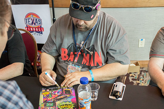 Batman 66 artist Christopher Franchi signs a flyer for the game
