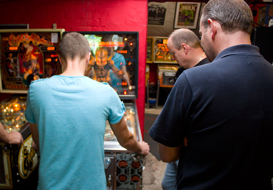 Dave Langley and Phil Dixon watch Greg Mott play Space Invaders