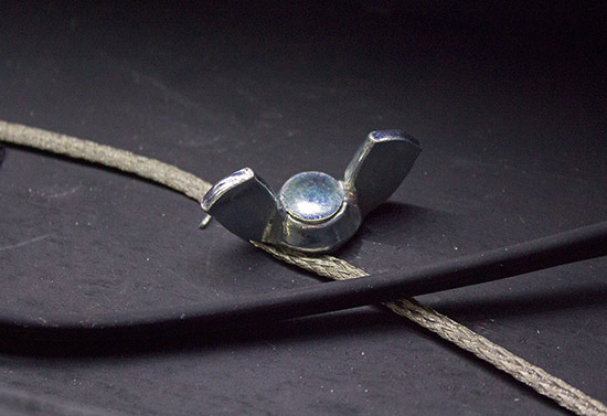 The ground braid is clamped by the backbox bolts