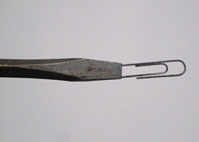 The screwdriver now holds the paperclip more solidly