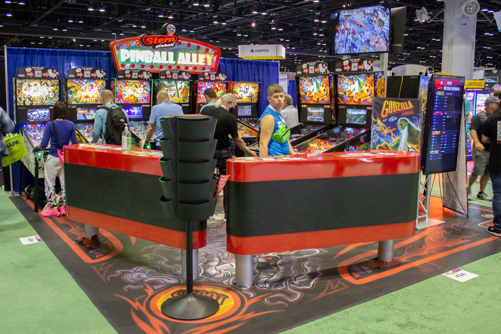 The Stern Pinball stand with flipper tables and a playfield carpet