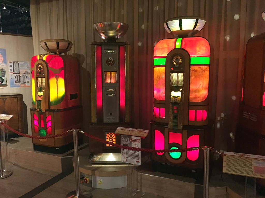Brightly-coloured jukeboxes on display include the Rock Ola Tone Column